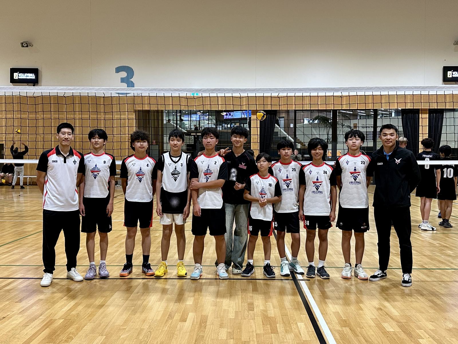 Falcons junior boys team lined up at the net with their coaches