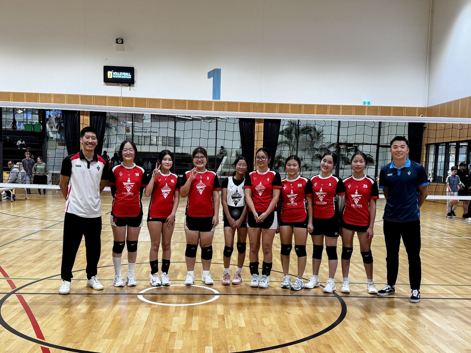 Falcons junior girls team lined up at the net with their coaches